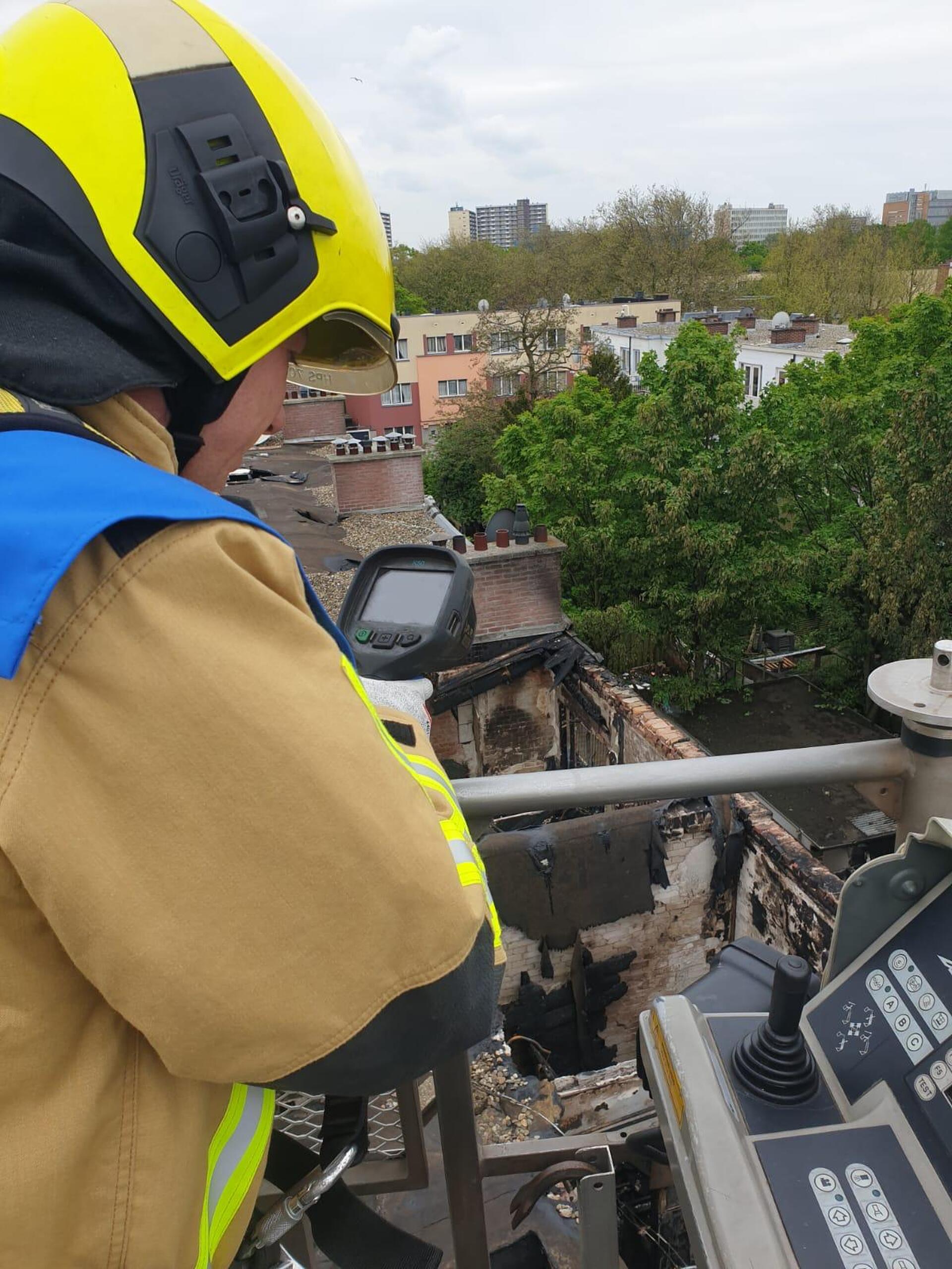 Brandweerman doet een nacontrole met een warmtebeeldcamera na indicent