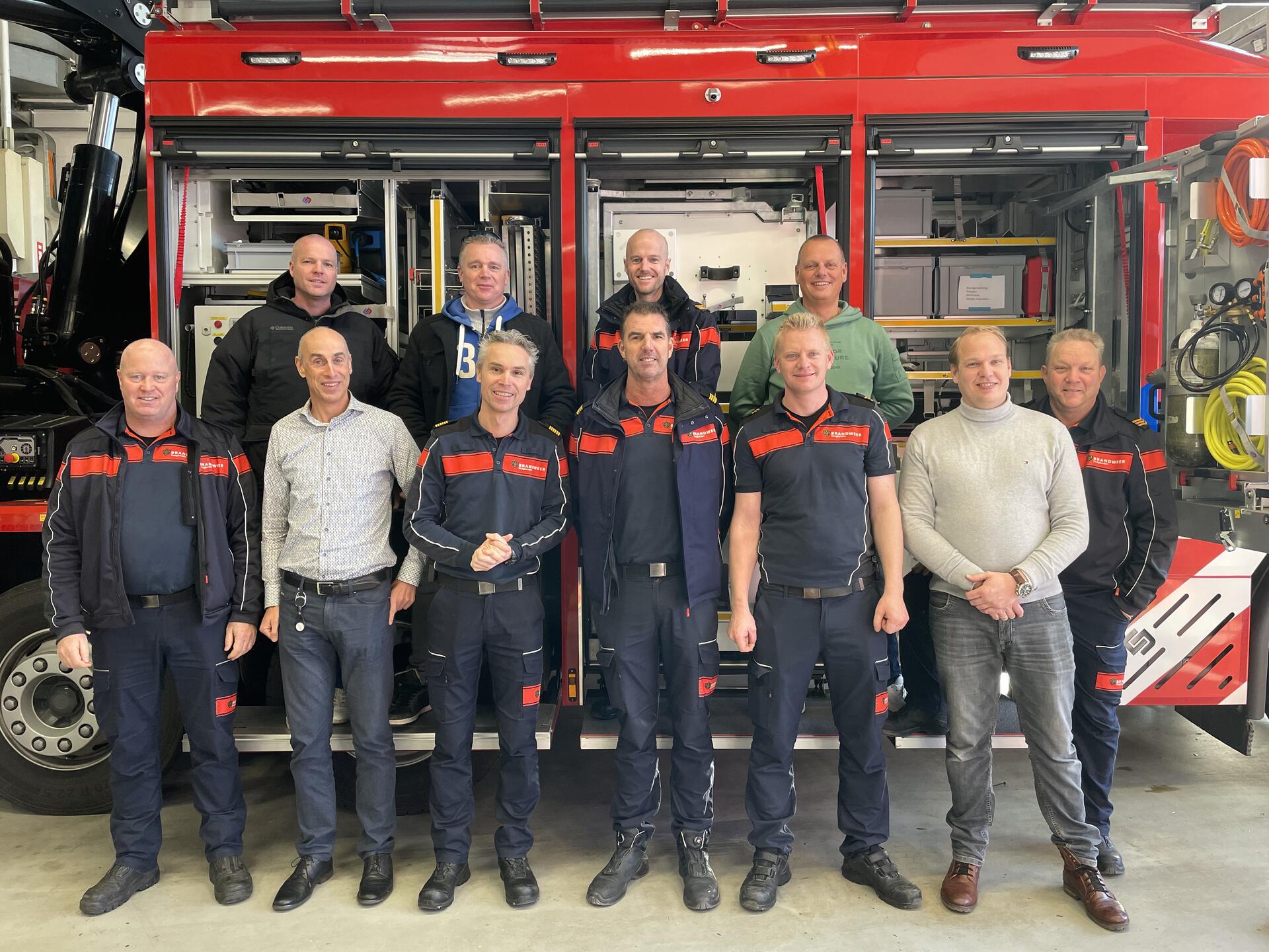 De werkgroep met 11 brandweermannen poseren voor het hulpverleningsvoertuig