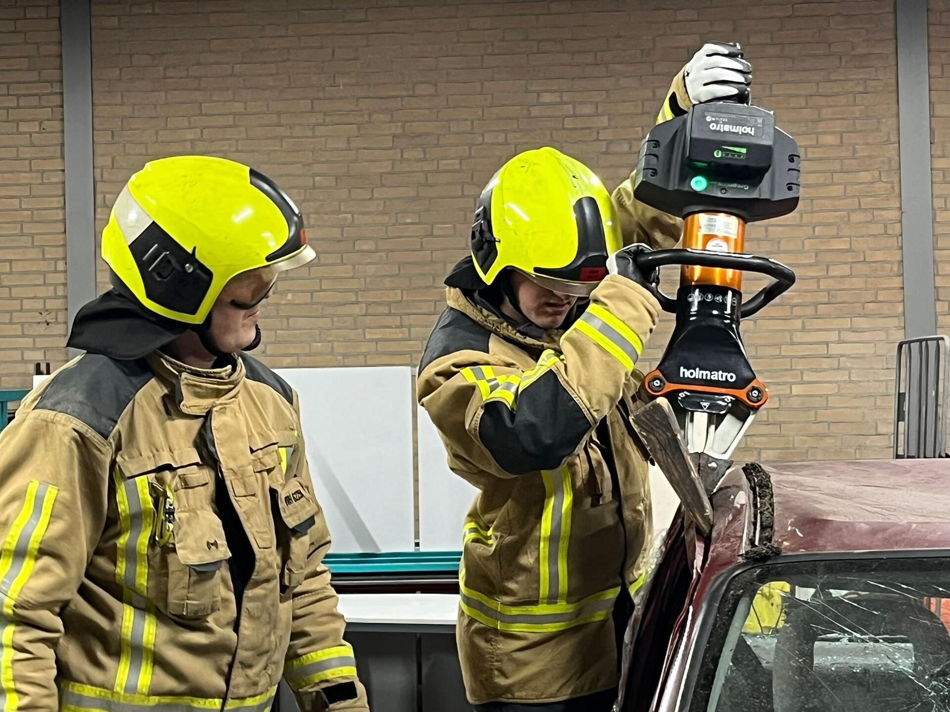 Twee brandweermannen openen autowrak met gereedschap