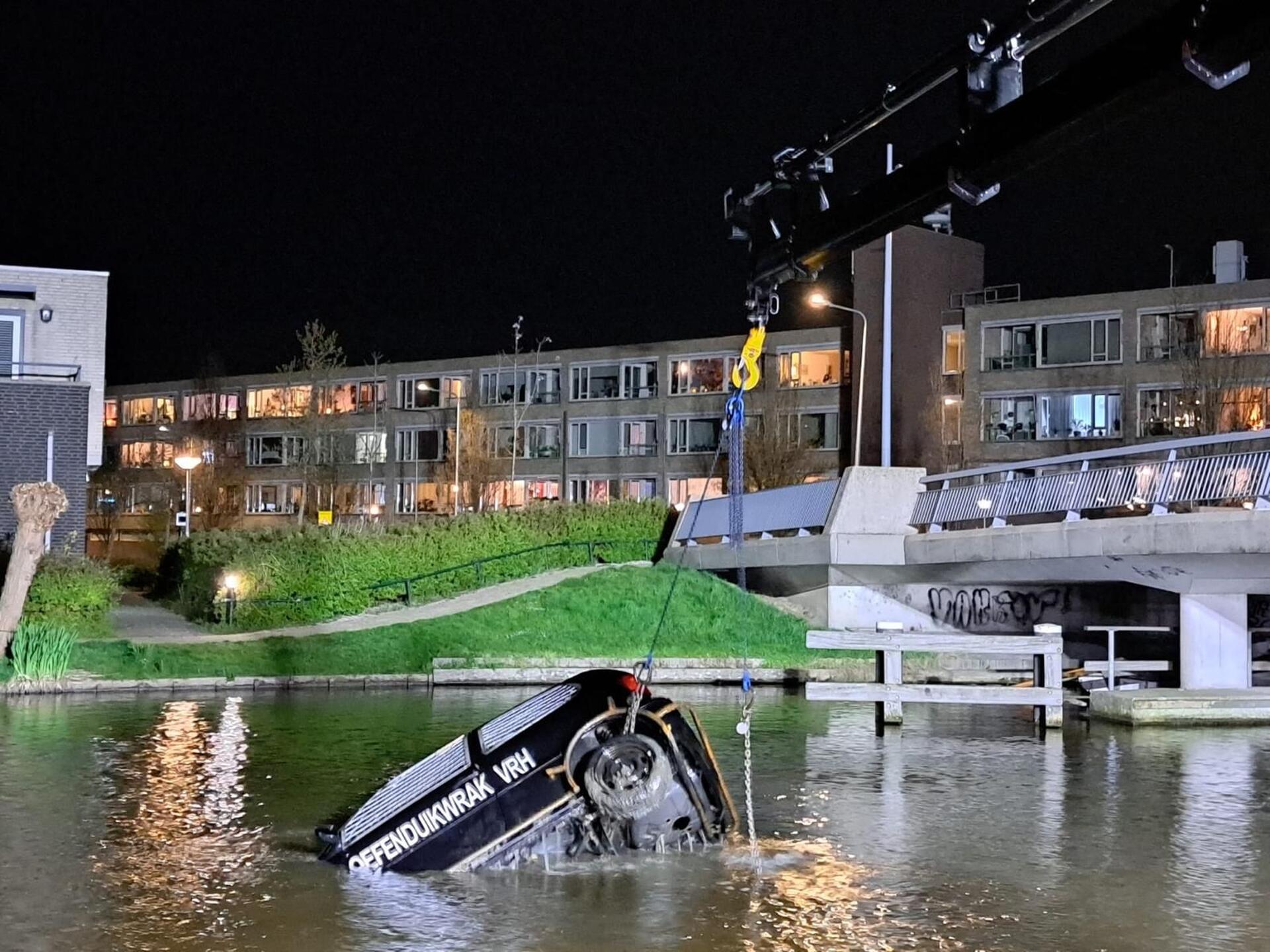 Foto in donker water waarop het zwarte duurzame autowrak zinkt 