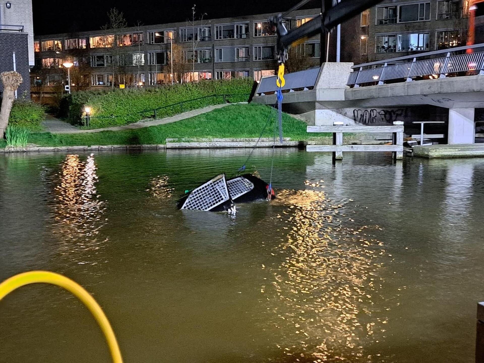 Foto in donker water waarop het zwarte duurzame autowrak zinkt 