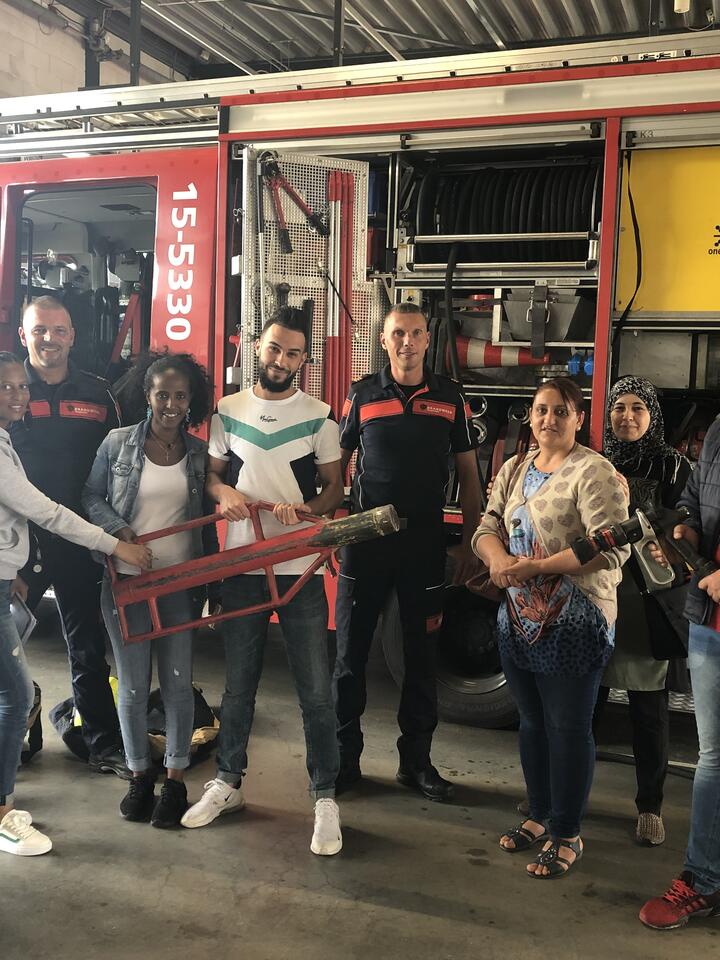Groep inburgeraars poseert voor brandweerwagen bij kazerne Oosterheem