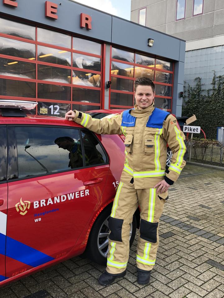 Brandweerman Mike van Velzen poseert naast brandweerauto