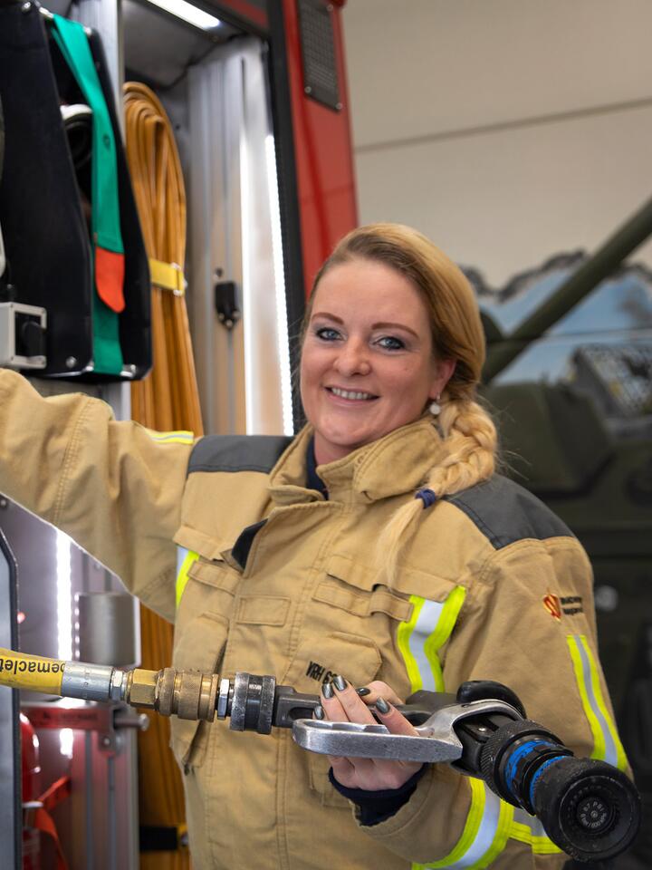 Brandweervrijwilliger Marije poseert voor brandweerwagen