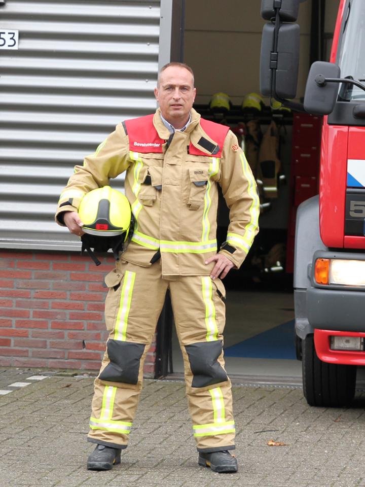 Bevelvoerder John poseert met helm bij brandweerwagen