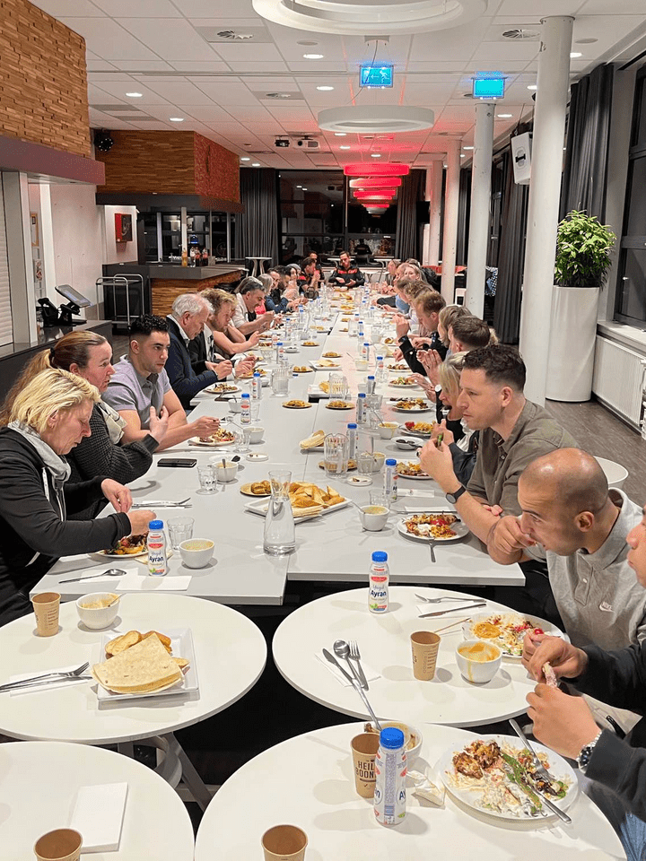 Groep mensen aan het eten aan een lange tafel