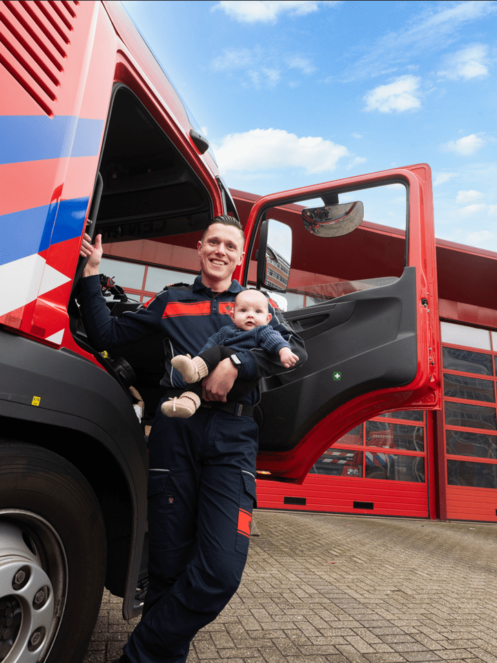 Yuri in uniform voor een tankautospuit met zijn zoon in zijn arm 