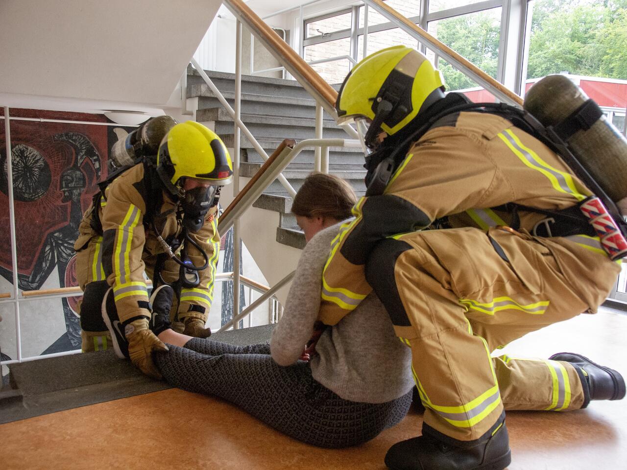 Brandweermensen helpen vrouw in trappenhuis