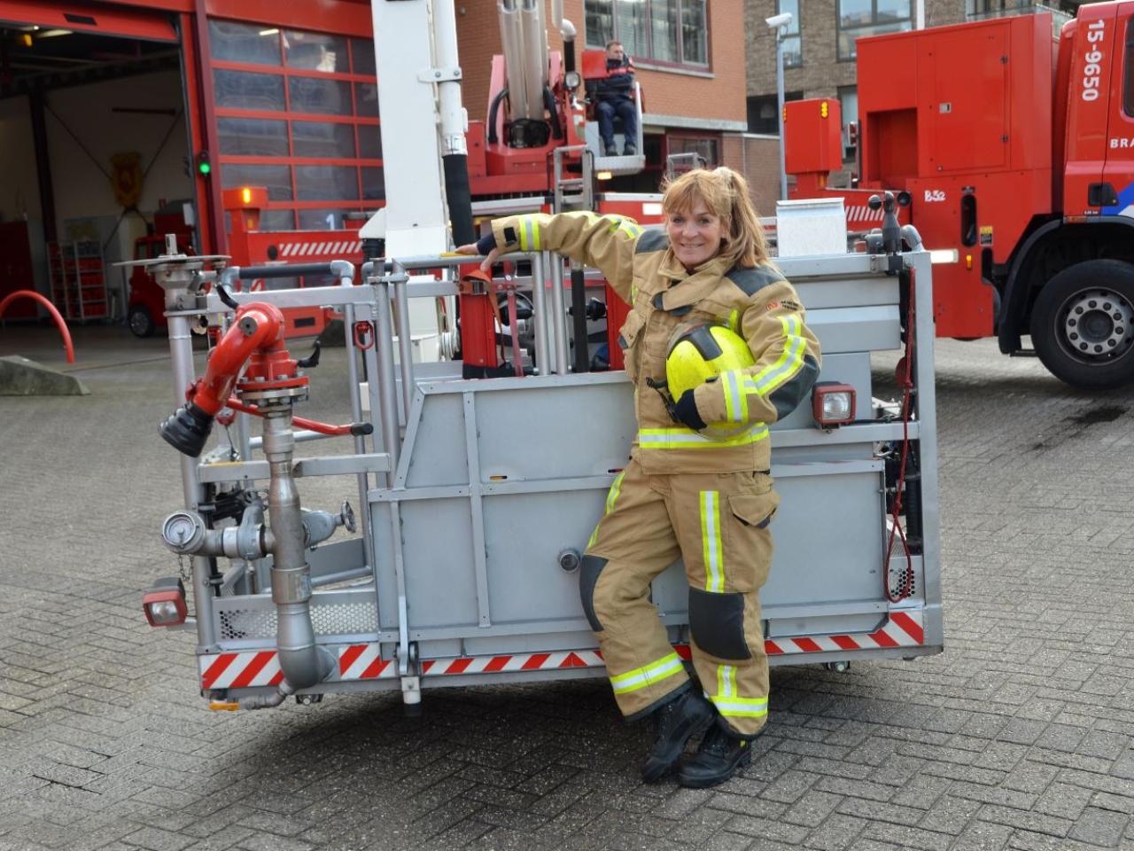 Brandweervrouw Els Nelis poseert bij hoogwerker