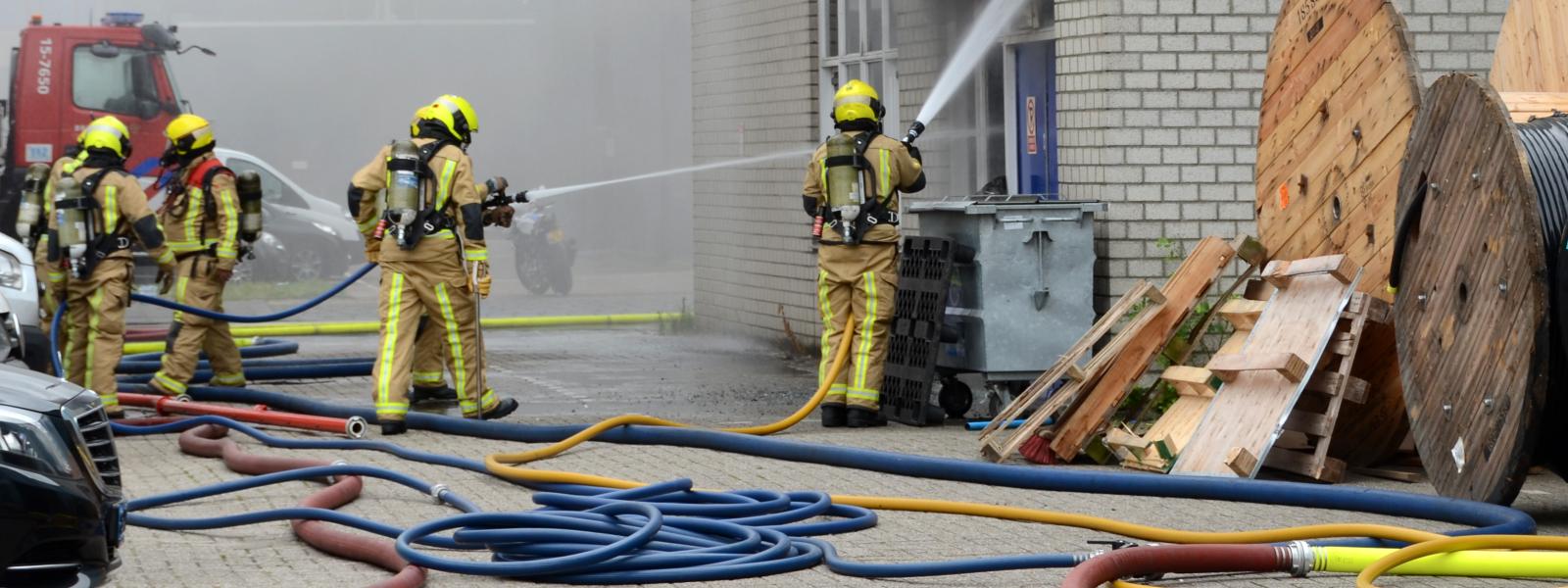 Brandweermensen blussen gebouwbrand
