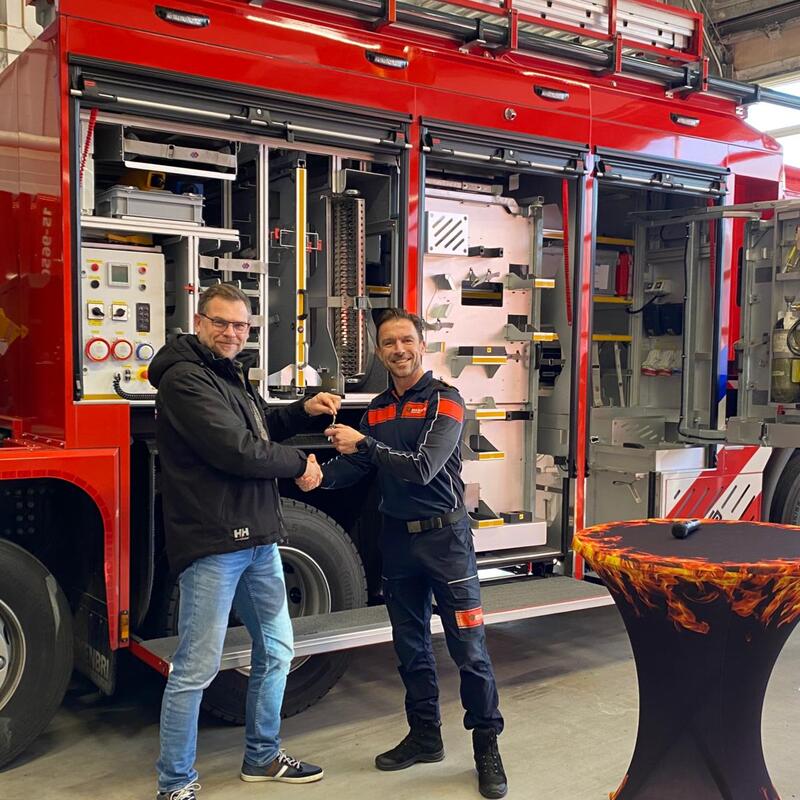 Directeur Brandweerzorg krijgt de sleutel van de leverancier en ze schudden elkaar de hand. 