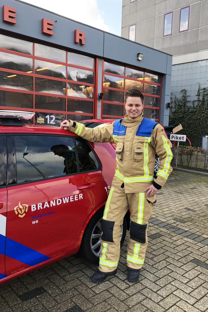 Brandweerman Mike van Velzen poseert naast brandweerauto