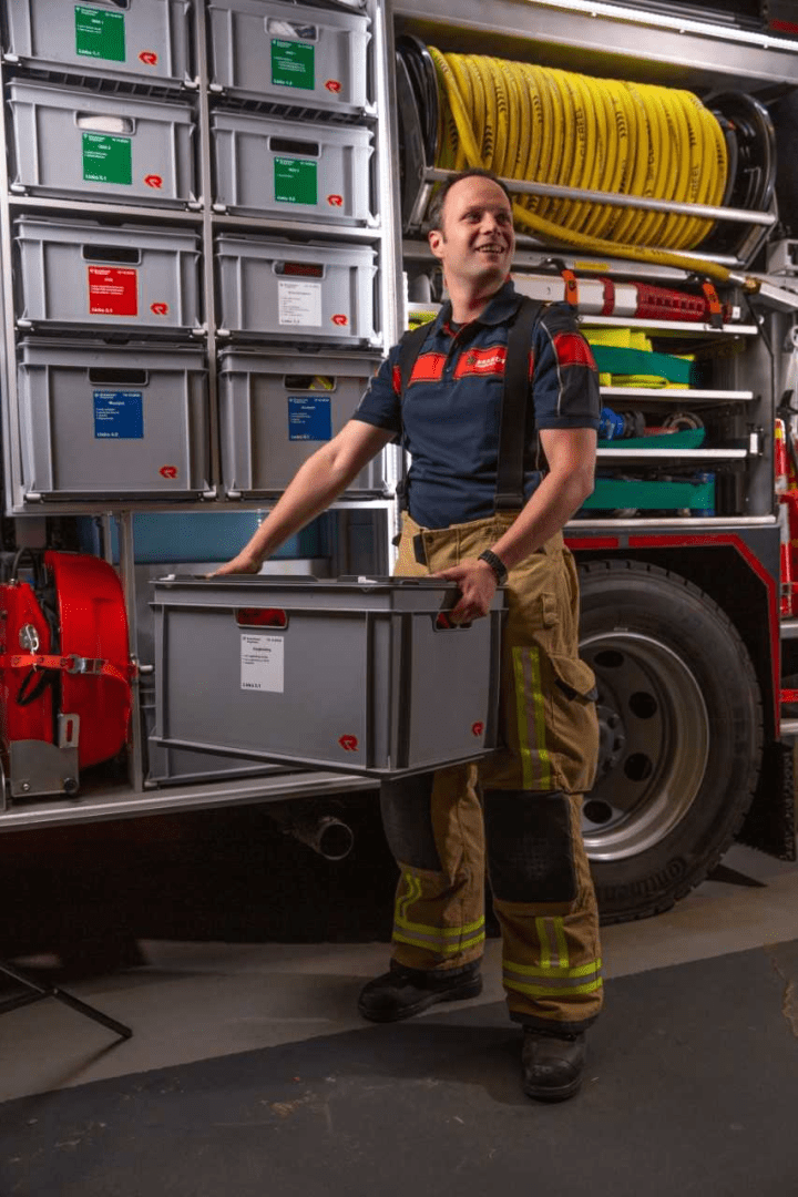 Brandweerman Gideon poseert naast brandweerwagen
