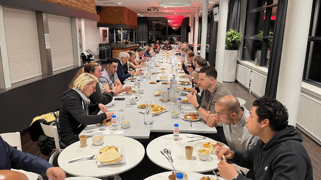 Groep mensen aan het eten aan een lange tafel