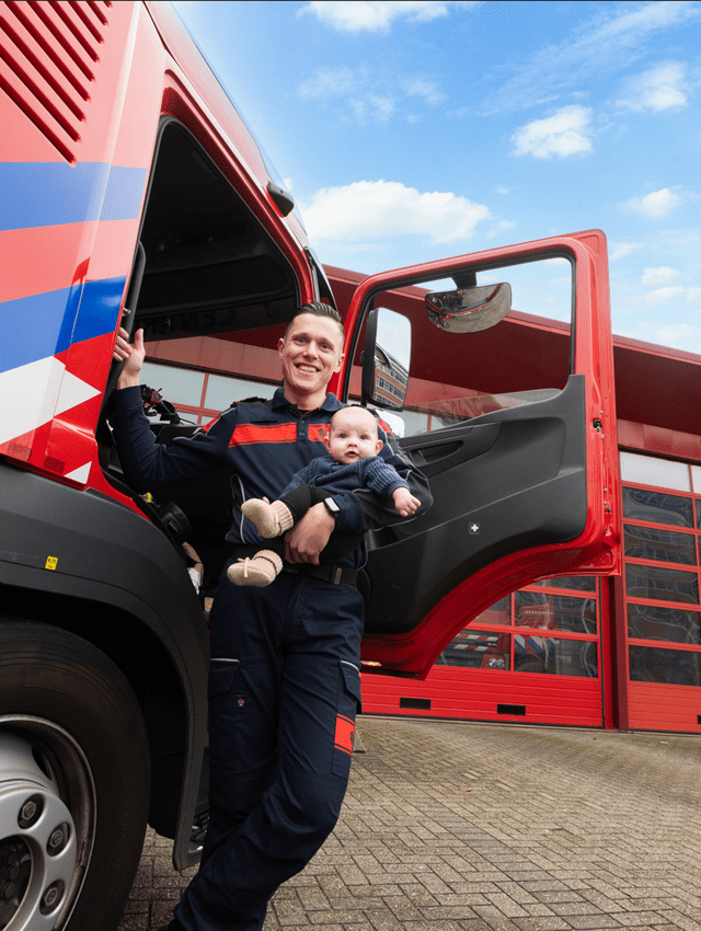 Yuri in uniform voor een tankautospuit met zijn zoon in zijn arm 