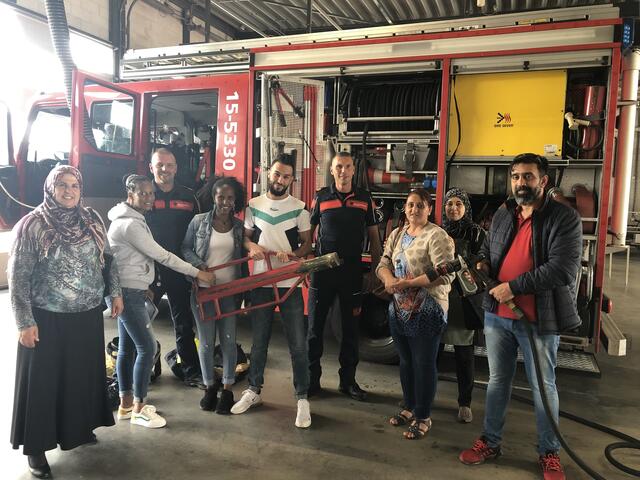 Groep inburgeraars poseert voor brandweerwagen bij kazerne Oosterheem